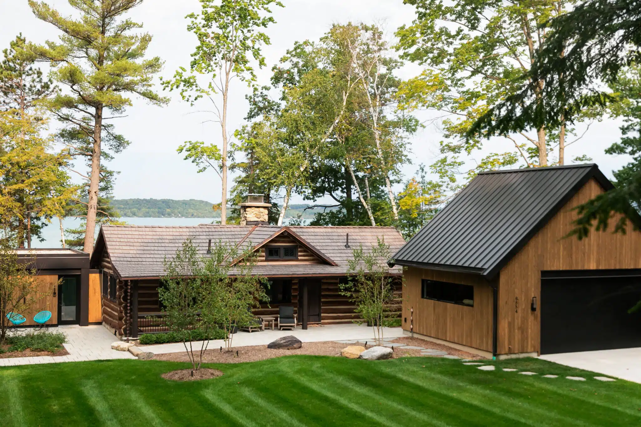 Lakefront log home with a black standing seam addition on Torch Lake