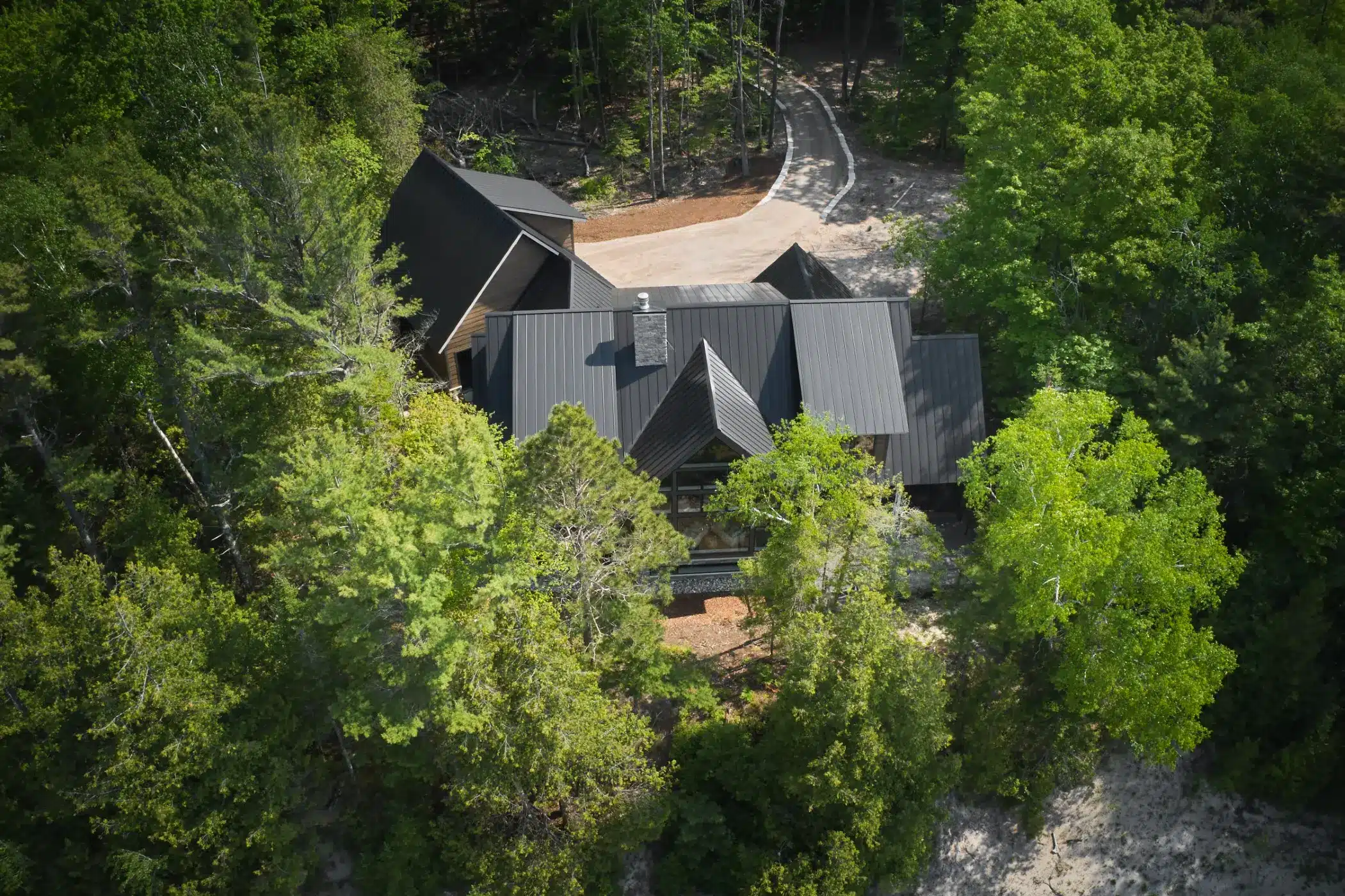Aerial view of a black standing seam metal roof in the woods in Northport MI