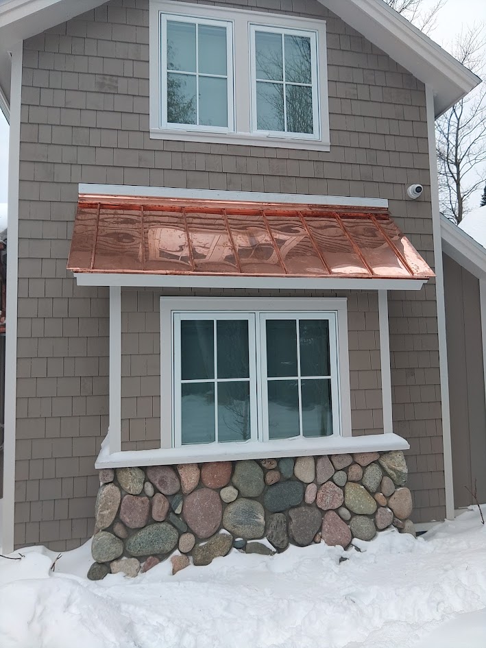 Copper standing seam accent roof detail over a window in Eastport MI