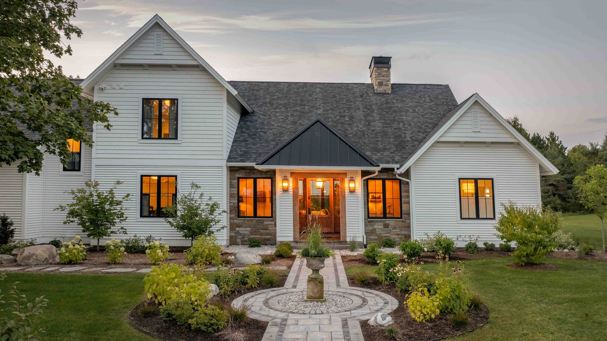 White farmhouse with a black standing seam porch roof at dusk in Lake Leelanau MI