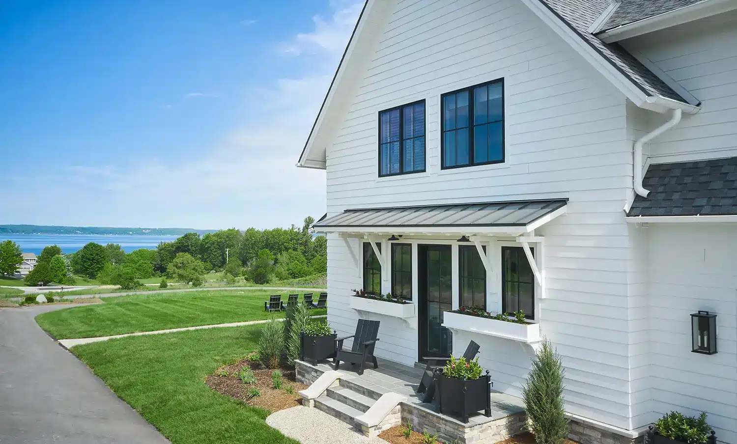 White farmhouse with a standing seam porch awning overlooking the bay in Old Mission MI