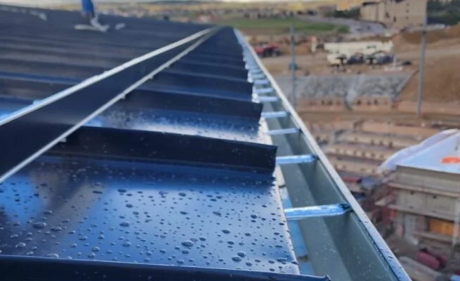 ColorGard snow fence installed along the eave of a dark standing seam metal roof