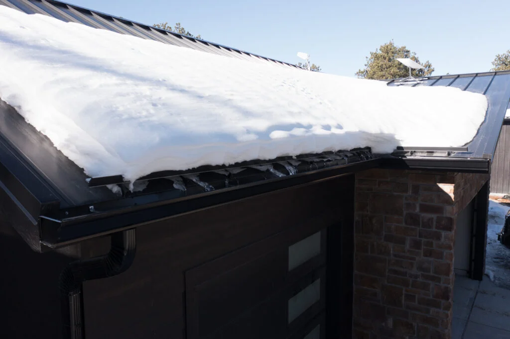 S-5 ColorGard snow fence holding snow on a black standing seam metal roof